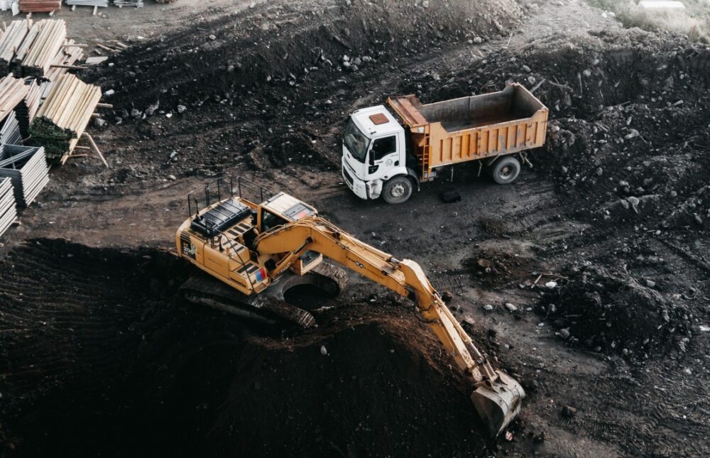 Heavy-duty excavator loading soil into a dump truck at an active commercial construction site in Texas