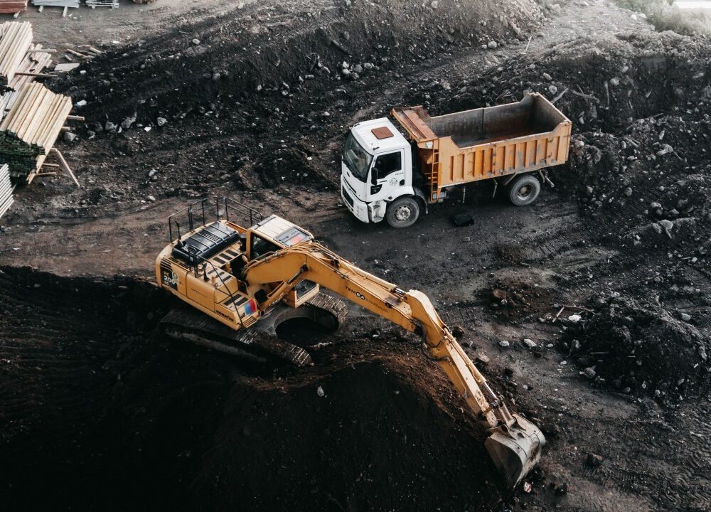 Site Excavation Heavy-duty excavator loading soil into a dump truck at an active commercial construction site in Texas